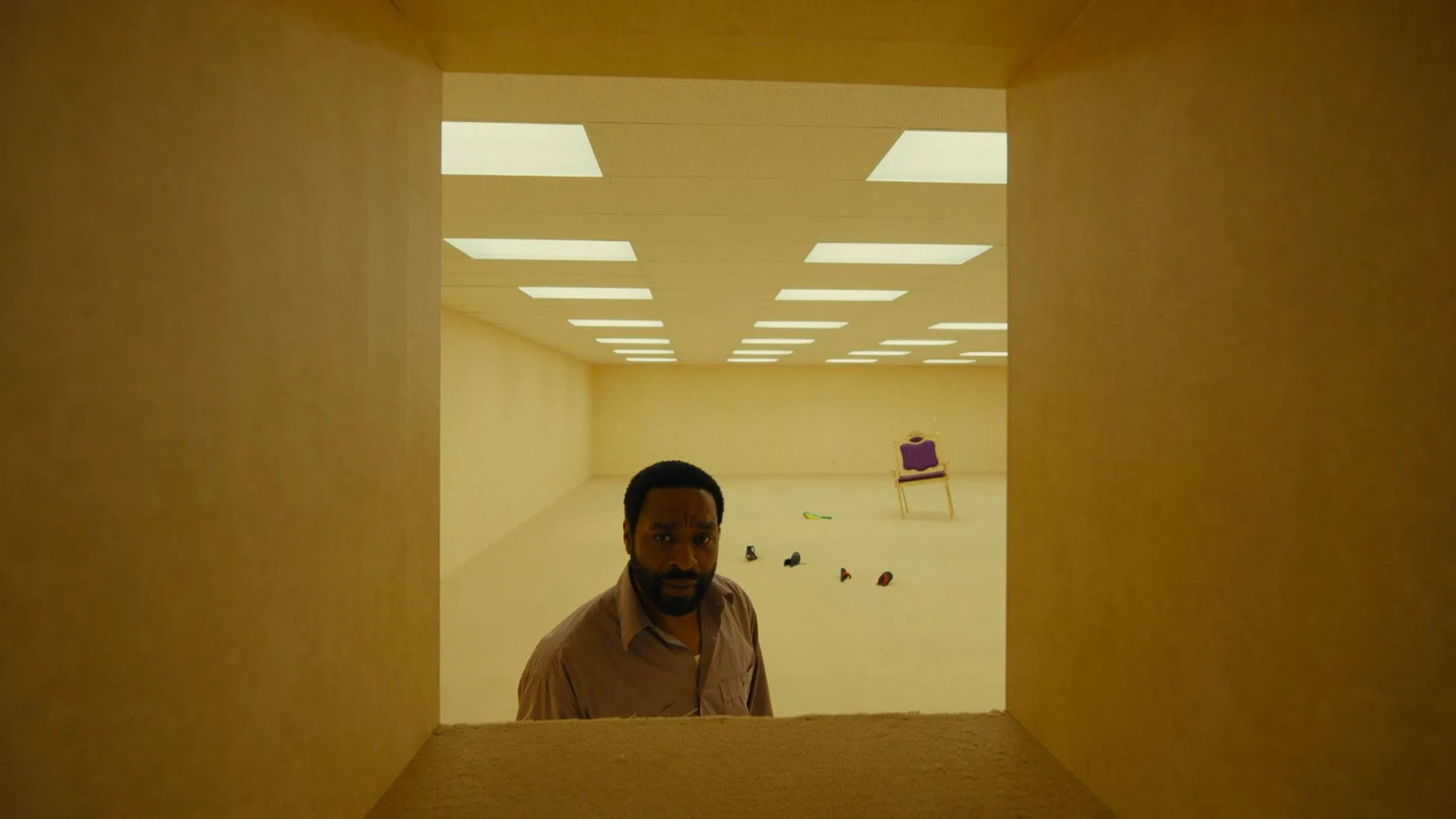 Chiwetel Ejiofor looking through a passageway in a yellow office